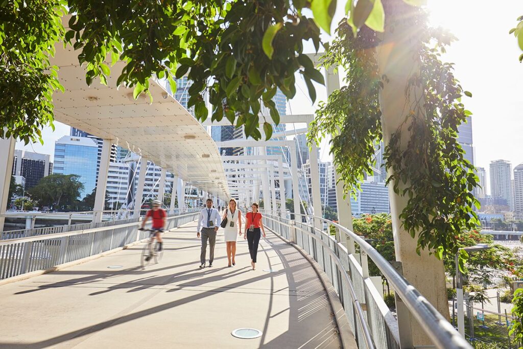 Three business people walking on a bridge and a cyclist passing by_Brisbane City